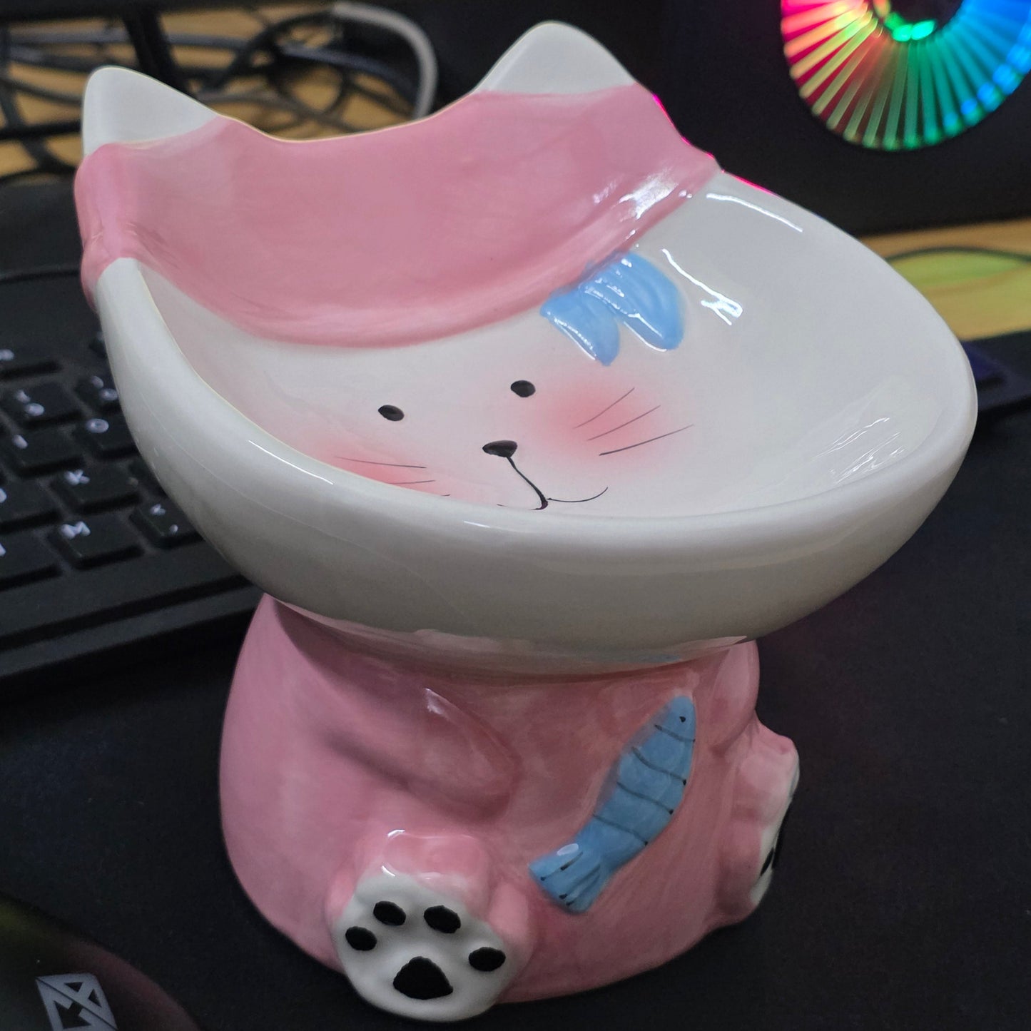 Pink cartoonish piggy bank on a keyboard with colorful fan in the background
